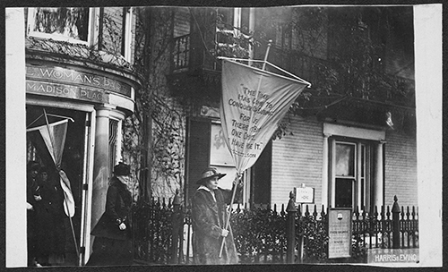 caption: The day after the police announced that future picket attendees would be arrested and sentenced, Alice Paul led a picket line with a banner reading “The time has come to conquer or submit for there is but one choice— we have made it.” Ms. Paul was sentenced to six months in prison.