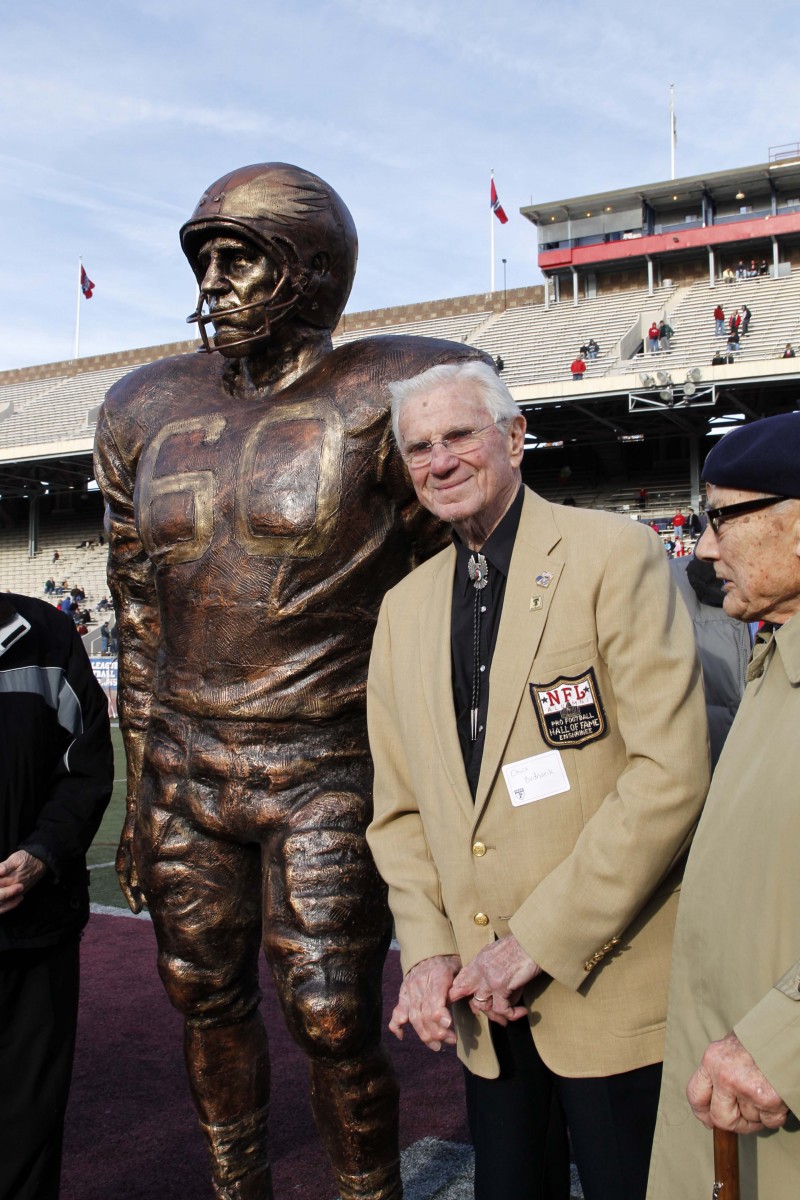 caption: Chuck Bednarik, Class of 1949, next to his statue inside Gate 2 on the north side of Franklin Field in 2011 when it was unveiled.