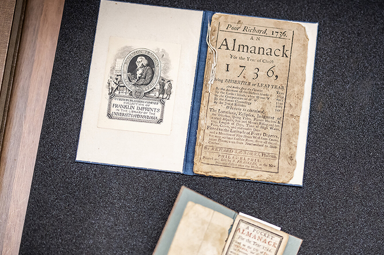 caption: The Libraries collection has several copies of Franklin’s Poor Richard’s Almanack, which he wrote and printed, including pocket-sized versions. Franklin’s mahogany partner desk is on the sixth floor of the Van Pelt Dietrich-Library Center.