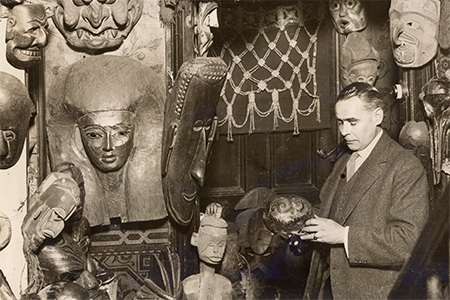 caption: In the Quotidian Pasts exhibit, W.O. Oldman with masks and headdresses, c. 1920, gelatin silver print, 8 X 10 inches.