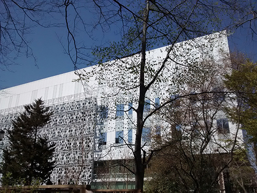 caption: The building’s design reflects its function in the ornate aluminum sunscreen with cutouts on the southern façade. The pattern of the sunscreen is designed to convey the branching and network structures found at all scales of biology and to resonate in psychological, linguistic and cognitive models. The sun screen also provides an element of sustainability, offering an expected minimal 50 percent reduction of solar heat gain during summer months.