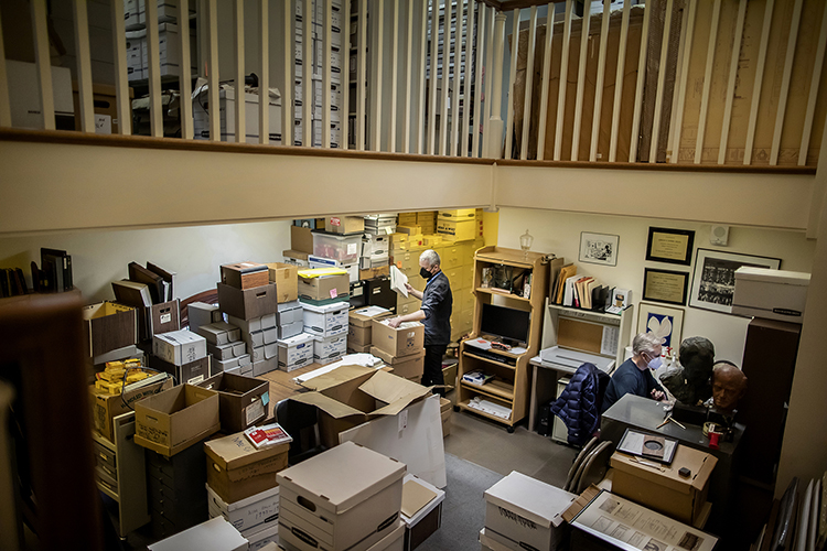 caption: Eric Dillalogue, Penn Libraries assistant director of operations at the Kislak Center (standing), and Darrin Britting, director of publications and content development at the Philadelphia Orchestra (seated), sort and pack the Philadelphia Orchestra records at the archives at the Academy of Music. 