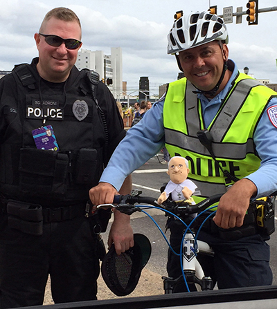 caption: Penn Police officers Jason Squadroni and Chris Denschuick on patrol with a miniature Pope Francis souvenir.