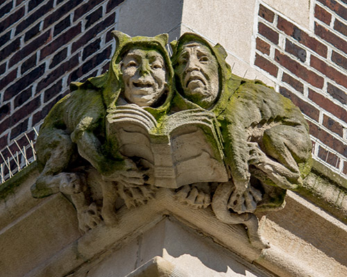 caption: On the exterior of the Quad, two mythical creatures share a book. 