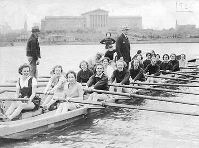 caption: Women and coaches on the Schuylkill River, with the Philadelphia Museum of Art in the background, in 1935 on the first day women were allowed to row.